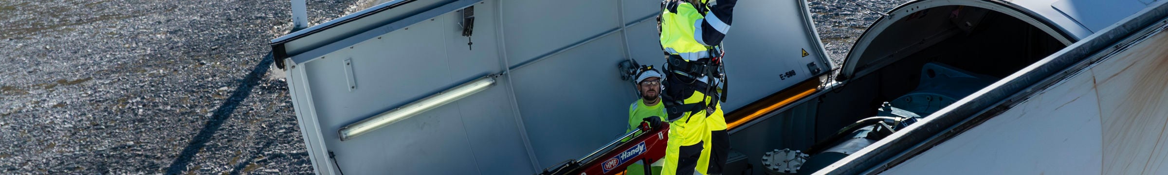 Person i varselkläder som utför underhållsarbete på toppen av en vindturbin.