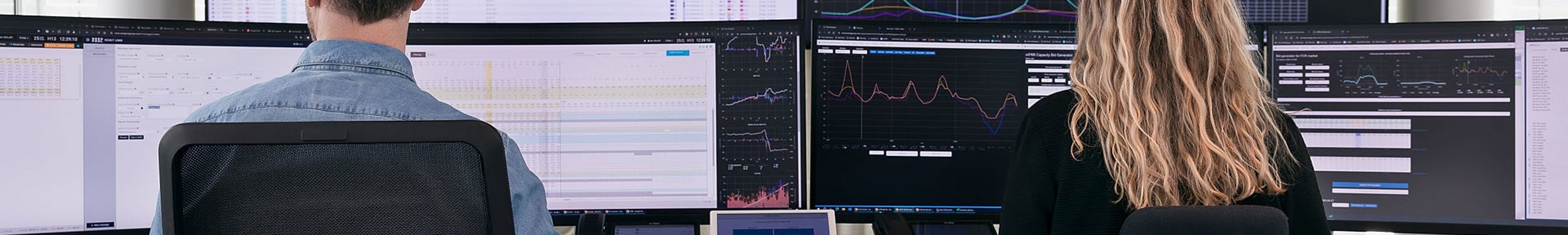 Två personer som sitter framför datorskärmar där stora datamängder uppvisas.